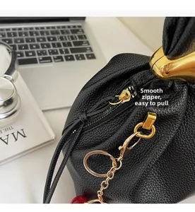 Close-up of premium black lychee leather bag featuring a smooth gold metal zipper closure
