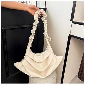 Close-up of cream pleated shoulder bag with lychee texture and bow tie strap detail