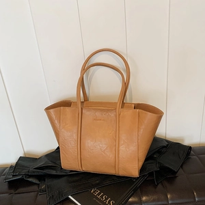 Detail shot of camel leather wing tote bag with FASHION embossed logo and soft texture