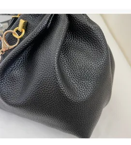 Detail of black lychee grain leather handbag showing soft texture and gold metal hook