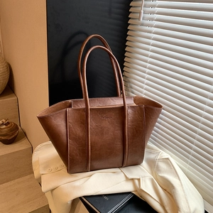 Detail of a brown leather tote bag with FASHION embossing in a stylish urban setting