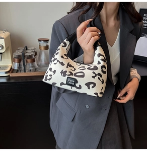 Detail of crescent leopard print handbag with brand label and leather trim detail