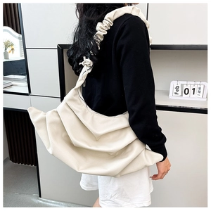 Close-up of beige ruched cloud bag showing textured lychee leather and ruffled strap details