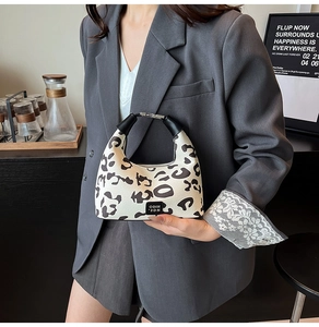 Detail of leopard print handbag with black leather logo label and stylish handle