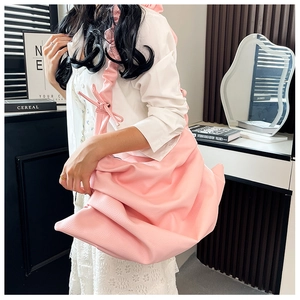 Pink lychee grain leather tote with pleated shoulder strap shown in a modern home setting