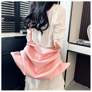 Detail of pink lychee leather shoulder bag with stylish pleated texture and knotted strap