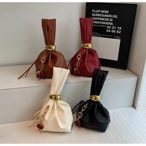 Detail of four pleated leather handbags with gold hardware and cherry charms in varied colors