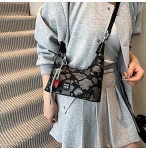 Detail of jacquard shoulder bag with silver tassels and a red heart charm