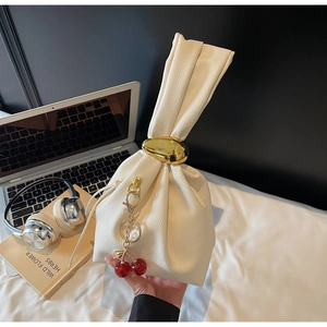 Creamy white lychee leather bag featuring a large gold ring closure and cherry charm detail