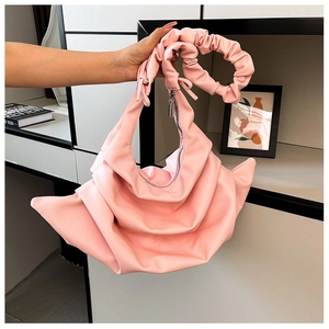 Detail of pink pleated handbag featuring textured leather and unique round ring handle