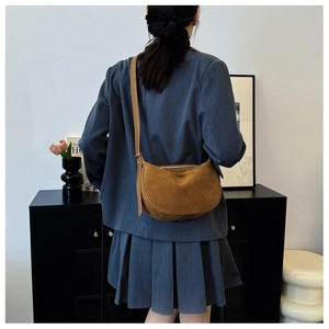 Brown suede crescent shoulder bag showing minimalist texture and retro style on model