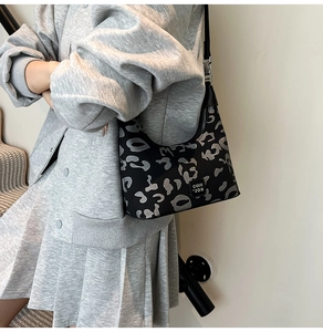 Detail of black leopard print dumpling bag with brand patch shown on model