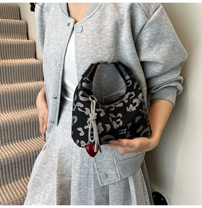 Close-up of leopard print handbag with silver chain and a red heart charm decoration
