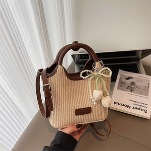 Stroh-Eimertasche mit braunem Leder und Perlen-Tulpen-Anhänger auf Schreibtisch