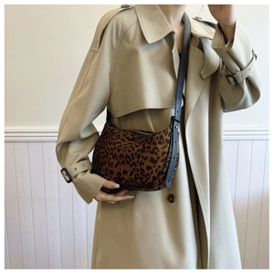 Close-up of leopard print crescent bag with suede texture and brown leather strap