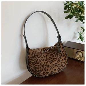 Close-up of leopard print hobo bag with black trim and metal zipper on wooden surface