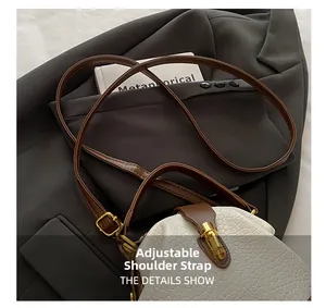 Detail of adjustable leather shoulder strap and golden metal buckle on a textured handbag