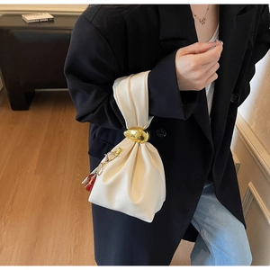 Detail of off-white pleated leather handbag with gold ring clasp and cherry charm