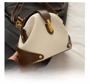 Detail of color-block leather handbag featuring gold twist lock and textured finish