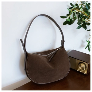 Detailed close-up of dark brown suede hobo bag featuring silver zipper and leather strap