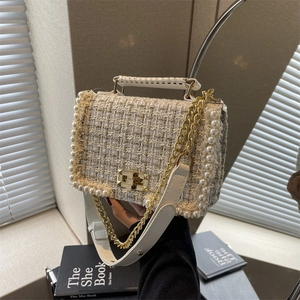 Elegant off-white tweed handbag with pearl trim and gold chain strap in natural light