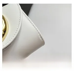 Detail of white leather handbag with gold hardware and precise stitching details