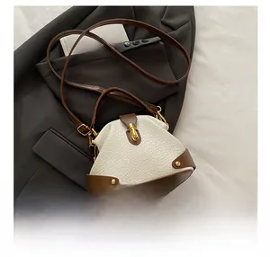 Close-up of retro white leather mini bag on suit jacket showing metal studs and hardware