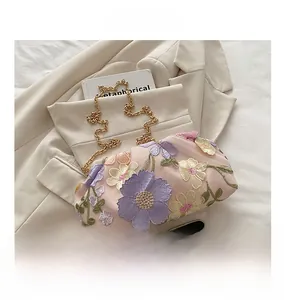 Détails de broderies florales et paillettes sur ce sac nuage élégant avec chaîne