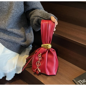 Detail of red lychee pattern leather bag with gold pebble ring and cherry charm