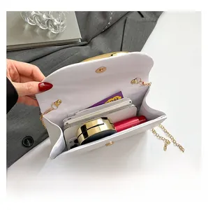 Internal view of a white minimalist evening bag with gold chain and storage space