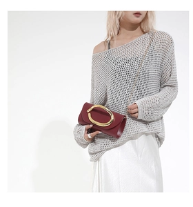 Close-up of a burgundy leather clutch with a large gold oval buckle and chain strap