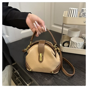 Close-up of a vintage beige pleated bucket bag with brown leather trim and gold metal clasp
