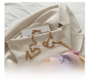 Vue détaillée de la broderie florale rose et de la bandoulière en chaîne dorée du sac