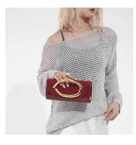 Detail of burgundy evening clutch bag with large oval gold metal buckle and handle