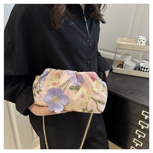 Détails de broderie florale et chaîne dorée sur pochette de soirée rose style nuage