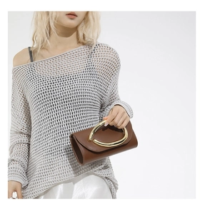 Detailed shot of brown leather clutch bag with elegant golden circular metal handle