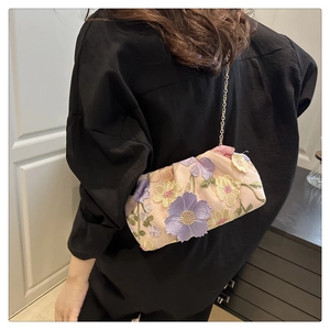 Détails des broderies florales et de la chaîne dorée sur le sac nuage rose