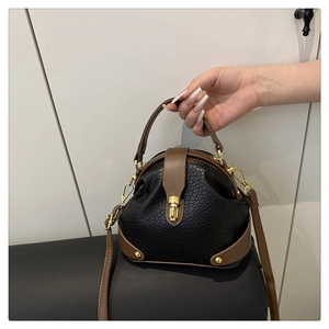 Detail of black croc-embossed doctor bag with brown leather trim and gold twist lock