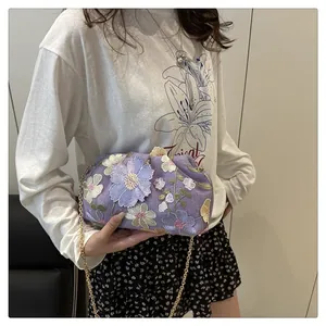 Détail de la broderie florale violette sur un sac de soirée nuage avec chaîne dorée