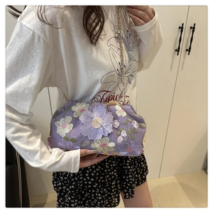 Détail de broderie florale violette sur un sac nuage avec chaîne dorée et paillettes