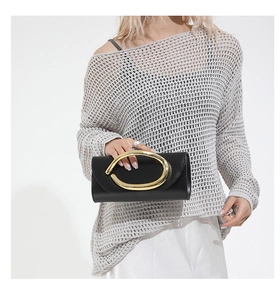Detail of minimalist black leather clutch with distinctive oval gold metal handle grip