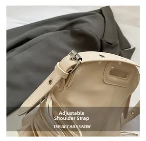 Détail de la bandoulière réglable avec œillets métalliques sur un sac crème à franges