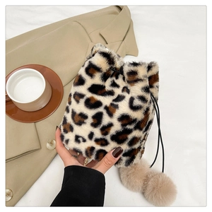 Detail of plush leopard print bucket bag featuring soft pom-poms and drawstring closure