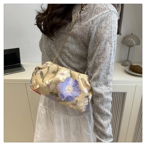 Détail de broderies florales sur pochette nuage beige avec bandoulière en chaîne