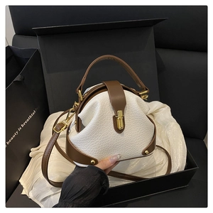 Close-up of contrast leather crossbody bag with gold buckle on elegant gift box background