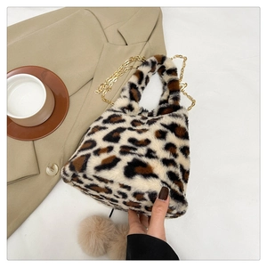 Detail of plush leopard print handbag with golden chain strap and soft pompom charms
