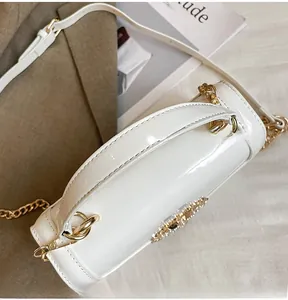 Detail of white patent leather barrel bag with gold sunflower buckle and chain strap
