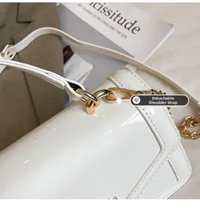 Detail of white patent leather shoulder bag with gold metal buckle and detachable strap