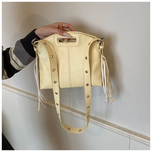 Détail du sac bandoulière jaune avec pompons latéraux et œillets métalliques sur la sangle