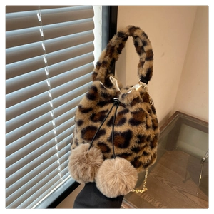 Detail of plush leopard print bucket bag featuring drawstring and fluffy pom-poms
